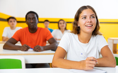 Young woman sitting at desk and listening to lecture in taxi training school.