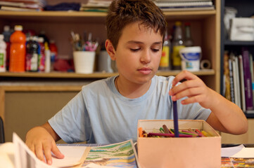 Young boy drawing with colored pencils in art class workshop