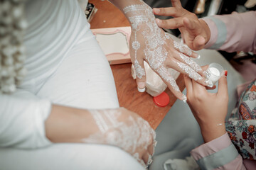 make white henna art on the bride's left hand