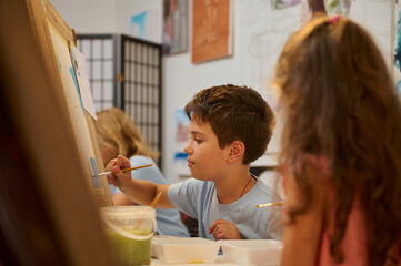 Children in art class painting and drawing with focus and creativity