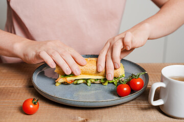Person Preparing Sandwich with Fresh Vegetables