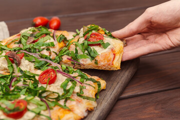 Hand Taking Slice of Napoli Pizza with Anchovy