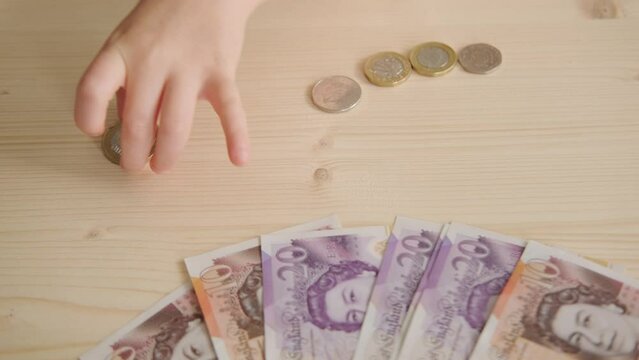 young child's hands carefully count and deposit coins into piggy bank, English pence and pounds, Financial literacy for kids, big goals, financial responsibility