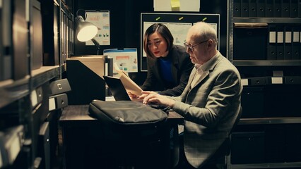 Team members cross reference data to track down potential suspect, using archived records and...