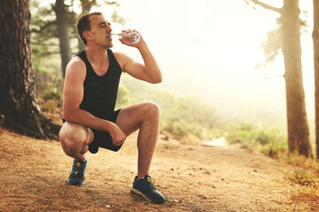 Man, nature and running with break for water or performance, exercise in countryside for wellness. Male runner, workout and stop for recovery with liquid thirst, outdoor for healthy body in Canada