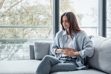Sick young woman in pain holding belly stomach feeling hurt abdomen ache gastritis pancreatitis...
