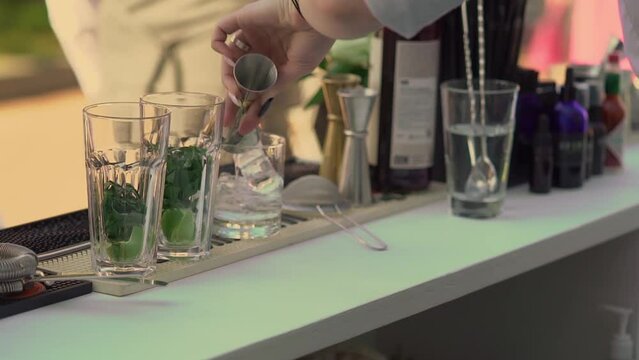 The waiter or bartender mixing cocktail in glasses. Welcome drink at a celebration or wedding reception in a restaurant or vacation bar. Alcoholic Beverage. Drinking straw.