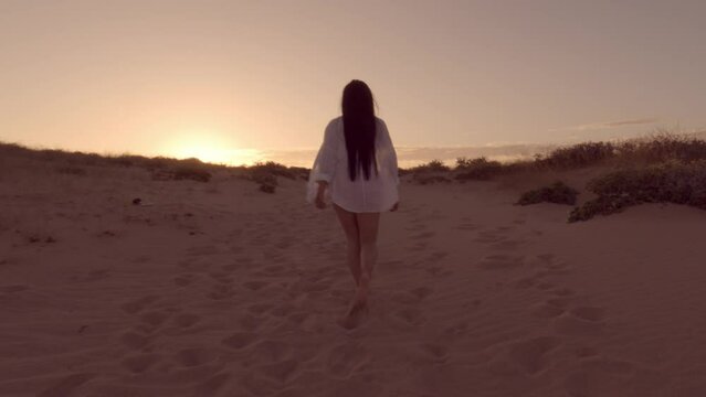Chica andando hacia la puesta de sol