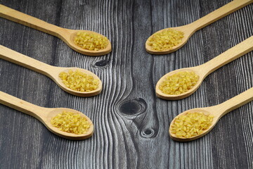 Dry bulgur wheat grains with a spoon close up