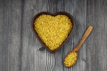 Dry bulgur wheat grains with a spoon close up