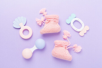 Pink baby booties and rattles on color background, top view