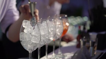 The waiter or bartender mixing cocktail in glasses. Welcome drink at a celebration or wedding reception in a restaurant or vacation bar. Alcoholic Beverage. Drinking straw.