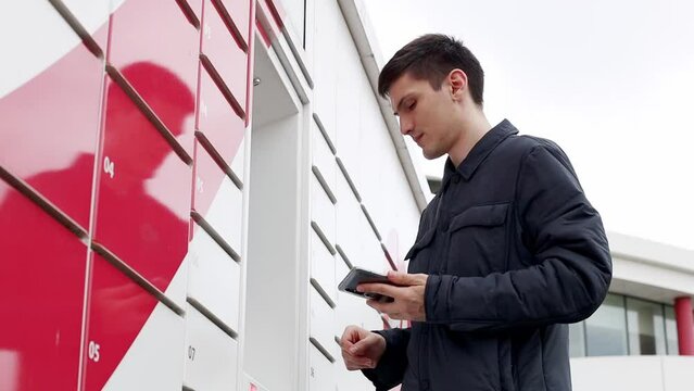 A young man scans a barcode with his phone to receive a package from a box.