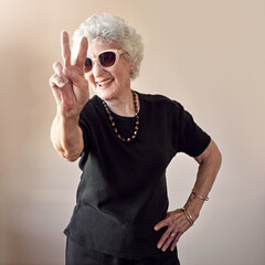 Fashion, sunglasses and senior grandma with peace sign on wall background for stylish, cool and...