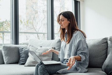 Angry young woman sit on sofa in living room frustrated having operational problems working on laptop, mad millennial girl feel stressed confused with slow internet connection or computer spam.