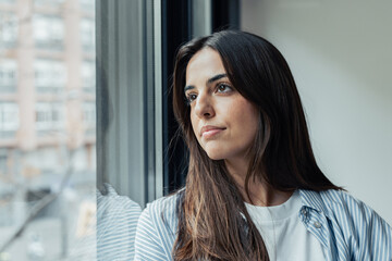 Unhappy thoughts. Worried young caucasian woman look at window feel lonely sad wait for boyfriend...