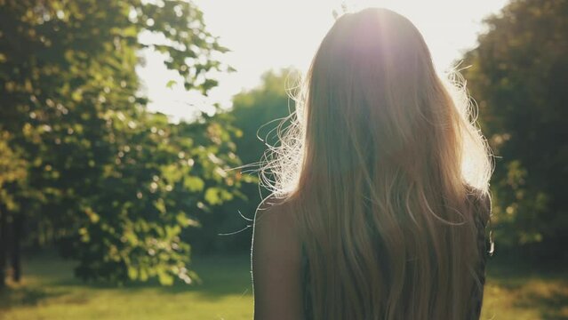 Portrait of a charming girl in a white skirt walking in the park at sunset. Slow motion