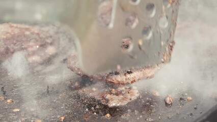 Flipping hamburgers grilling on a flat top grill outside in summer 