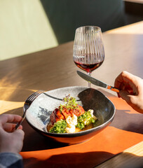 A close-up photo showcasing a delicious gourmet meal on a restaurant table, with hands holding...