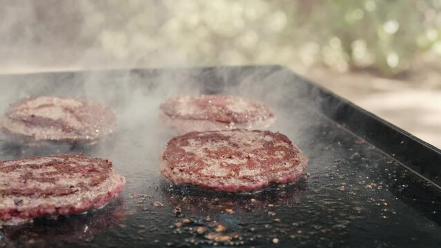 Hamburgers grilling on flat top outside in summer