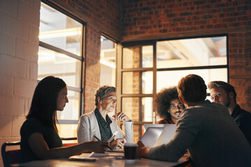 Business people, meeting and teamwork with laptop at night in office for newspaper review. Press, writers room and journalists with tech for article research, feedback and brainstorming together