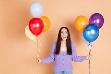 Portrait of nice young woman hold balloons wear cardigan isolated on beige color background