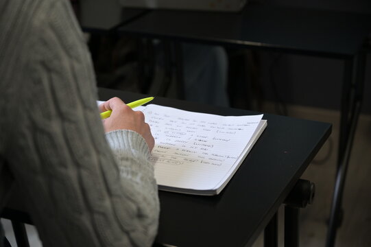 giovane donna prende appunti sul quaderno con una penna durante un corso d'inglese
