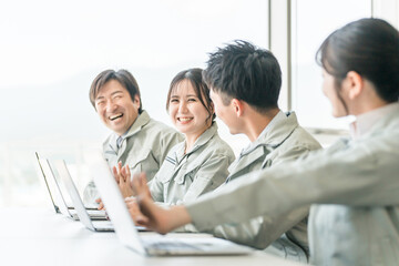 Fototapeta premium デスクワークする作業着・作業服姿の男女ビジネスマン・エンジニア（仕事終わり・休憩） 