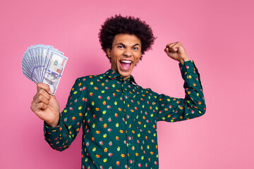 Portrait of overjoyed guy with wavy hair dressed print shirt holding money win gambling raising...