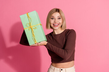 Photo of positive nice pretty girl wear trendy brown clothes showing gift isolated on pink color background