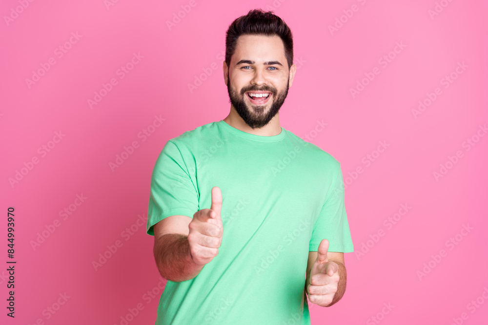 Wall mural Photo of cool handsome good mood nice guy with stylish beard dressed green t-shirt indicating at you isolated on pink color background