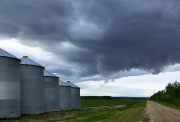 Stormy sky over old granaries along the country road.