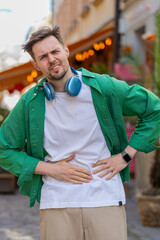 Caucasian young man traveler feeling sudden strong abdominal stomach ache, gastritis problem. Upset...