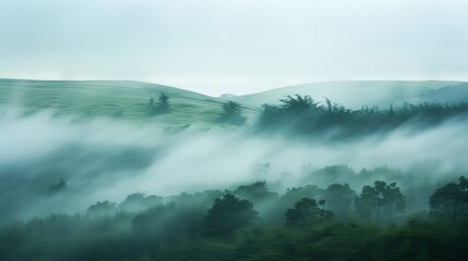 A blurred landscape of rolling hills and twisted trees shrouded in a misty cover of lowhanging clouds. .
