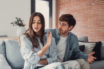 Beautiful lady is depressed, sitting on the couch talking to man, having a dispute with husband or...