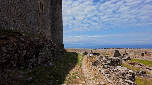 POV shot while walking along the outer wall of Medieval Chlemoutsi castle, Peloponnese, Kyllini-Andravida in Greece on a sunny day.