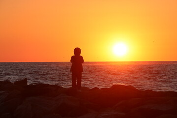 A figure silhouetted against the rising sun at a beach in Virginia