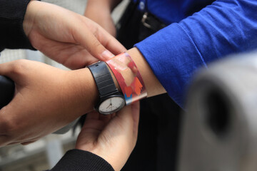 closeup other person putting a paper bracelet ticket