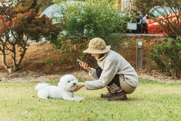 秋冬のキャンプ場で愛犬と遊ぶキャンパーのアジア人女性（ビジョンフリーゼ）
