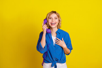 Portrait of pretty young lady speak telephone laugh wear blue shirt isolated on yellow color...
