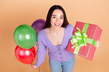 Above view portrait of nice young woman balloons giftbox wear cardigan isolated on beige color background