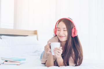 Happy asian woman use headphones listen to music from smartphone outdoor sitting on cozy sofa in living room at home. Music mental therapist for relaxation woman. Leisure cheerful wellness woman