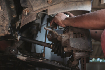 Close up Mechanic man hands repairing car auto repair shop uses jack change tyre. Man hands fixing Shock absorber machinery vehicle mechanical service. Vehicle Car overhaul maintenance engineer