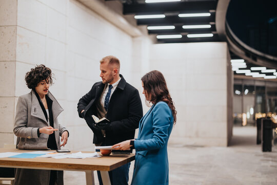 Multicultural Business Team Engaging In A Serious Business Discussion In Modern Office Corridor.