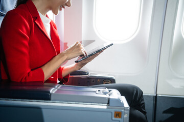 A woman in a formal suit sits in a window seat of an economy class section, looking out the airplane window, ready for her business journey.