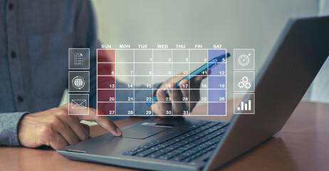Businessman uses index finger to set agenda on calendar as appointment planning concept.	