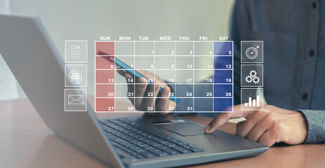Fototapeta premium Businessman uses index finger to set agenda on calendar as appointment planning concept. 