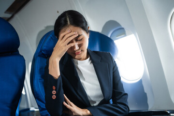 A woman in a formal suit sits in a window seat of an economy class section, looking out the airplane window, ready for her business journey.