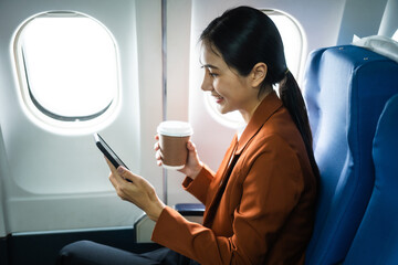 A woman in a formal suit sits in a window seat of an economy class section, looking out the airplane window, ready for her business journey.