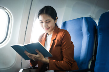 A woman in a formal suit sits in a window seat of an economy class section, looking out the airplane window, ready for her business journey.